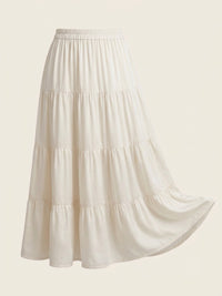 An off-white tiered skirt with an elastic waistband, shown against a solid cream background.